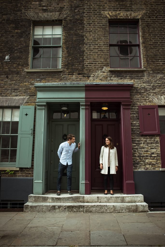 Couple smiling at each other across two brightly painted London doorways