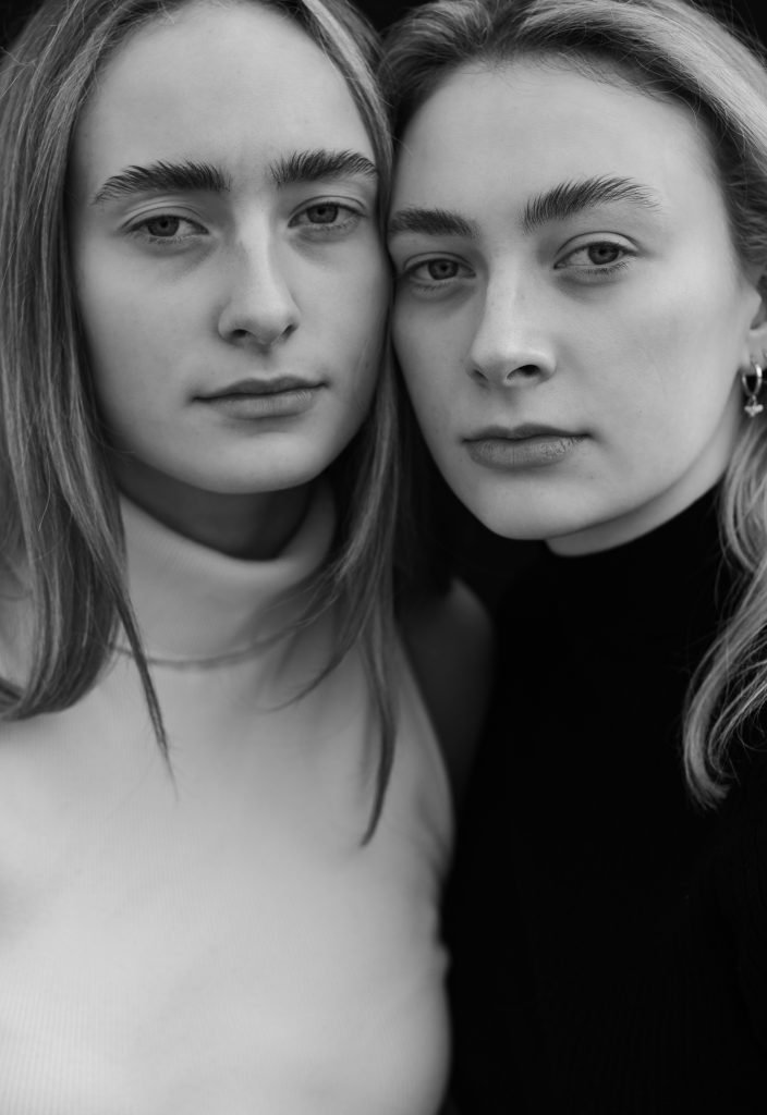 Close portrait of two sisters leaning together, black and white photograph