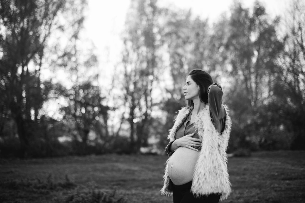 Pregnant woman standing in a meadow at golden hour, black and white photograph