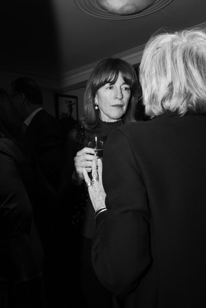 Guest holding a glass in conversation, black and white photograph
