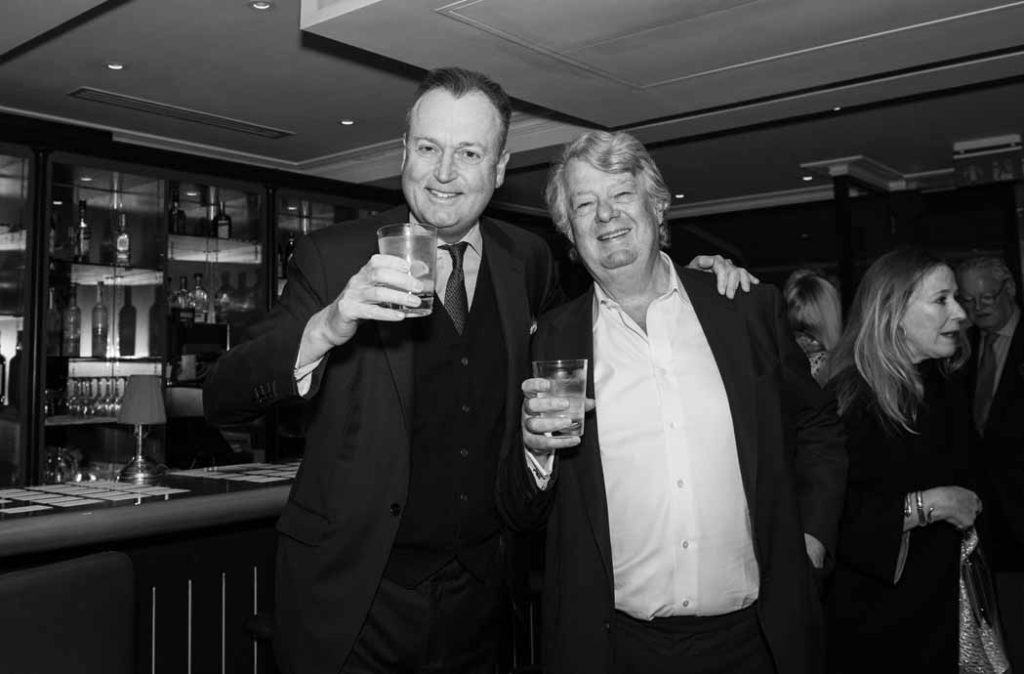 Two guests raising their drinks at the bar, black and white photograph