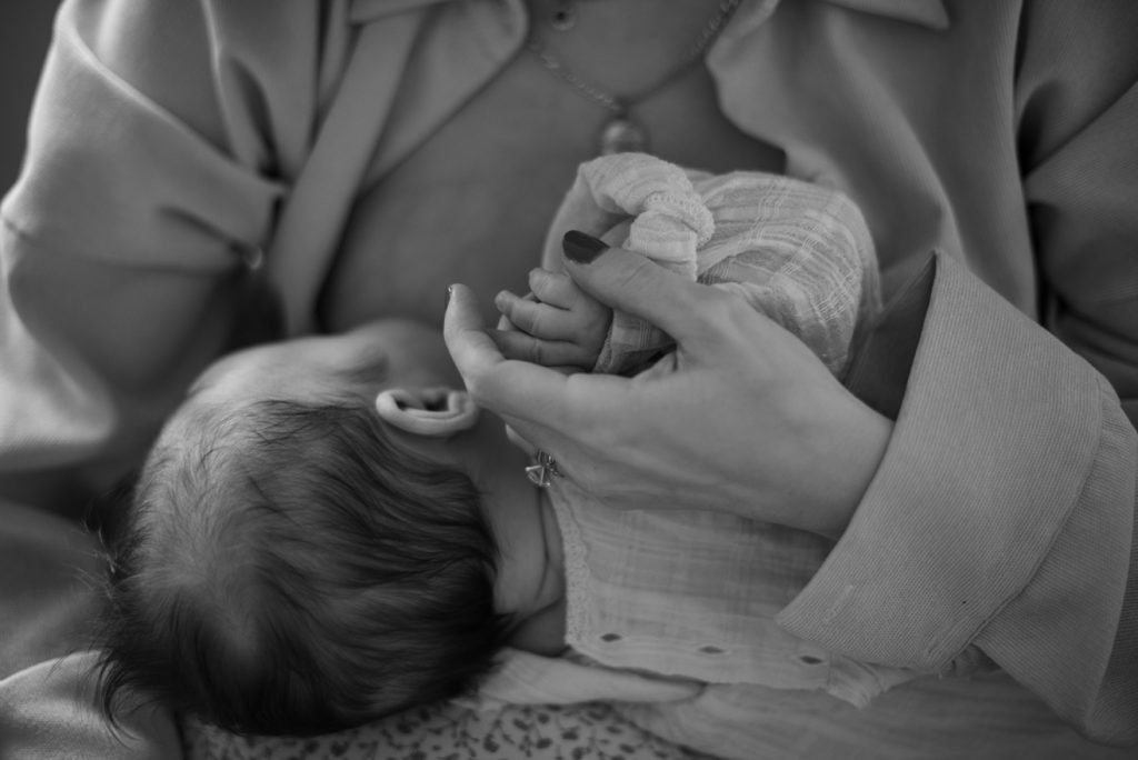 Newborn baby held against a parent's chest, black and white photograph