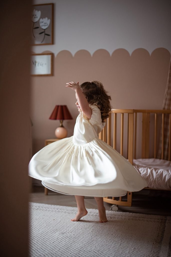 Small girl spinning in a party dress in her bedroom