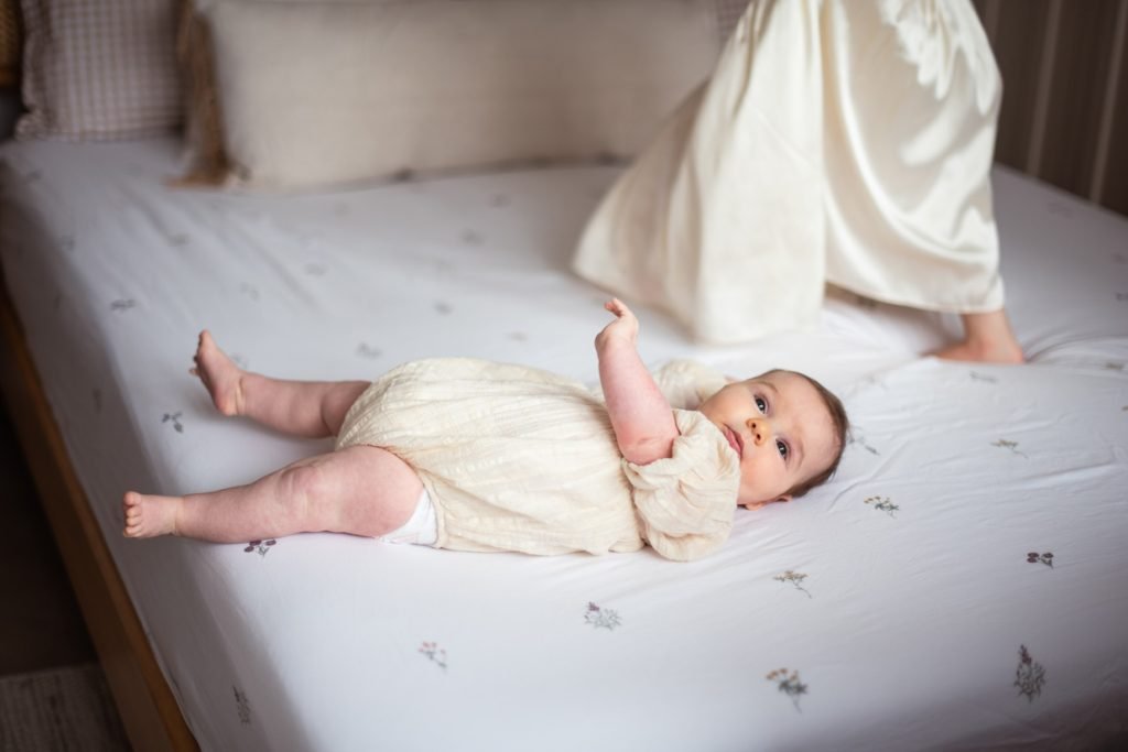 Newborn baby lying awake on a bed