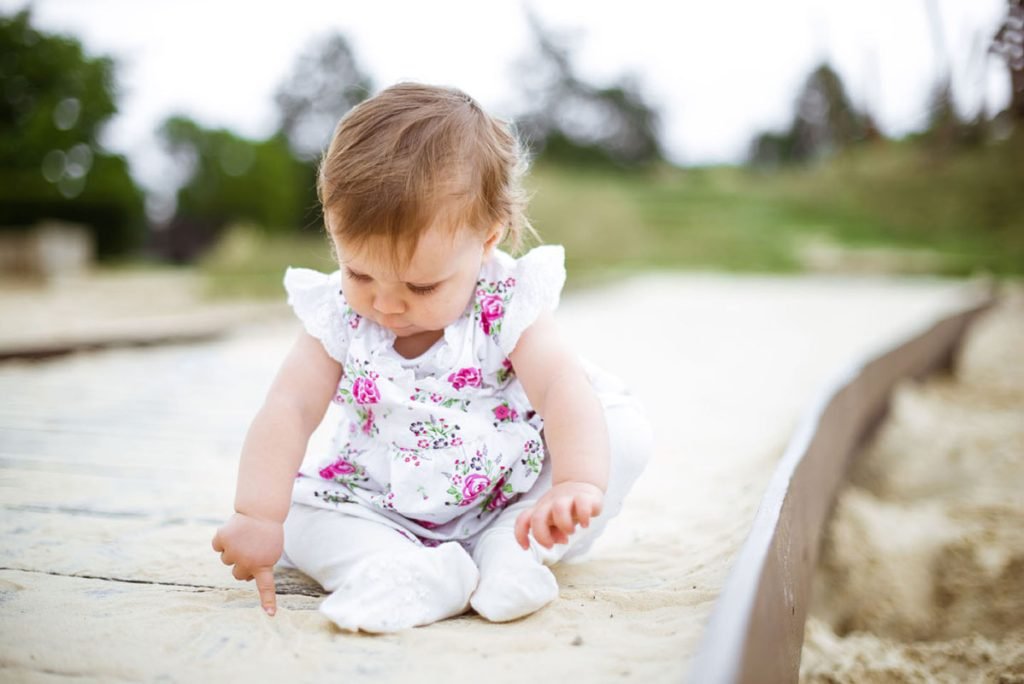 Toddler in a floral top sitting on a stone path