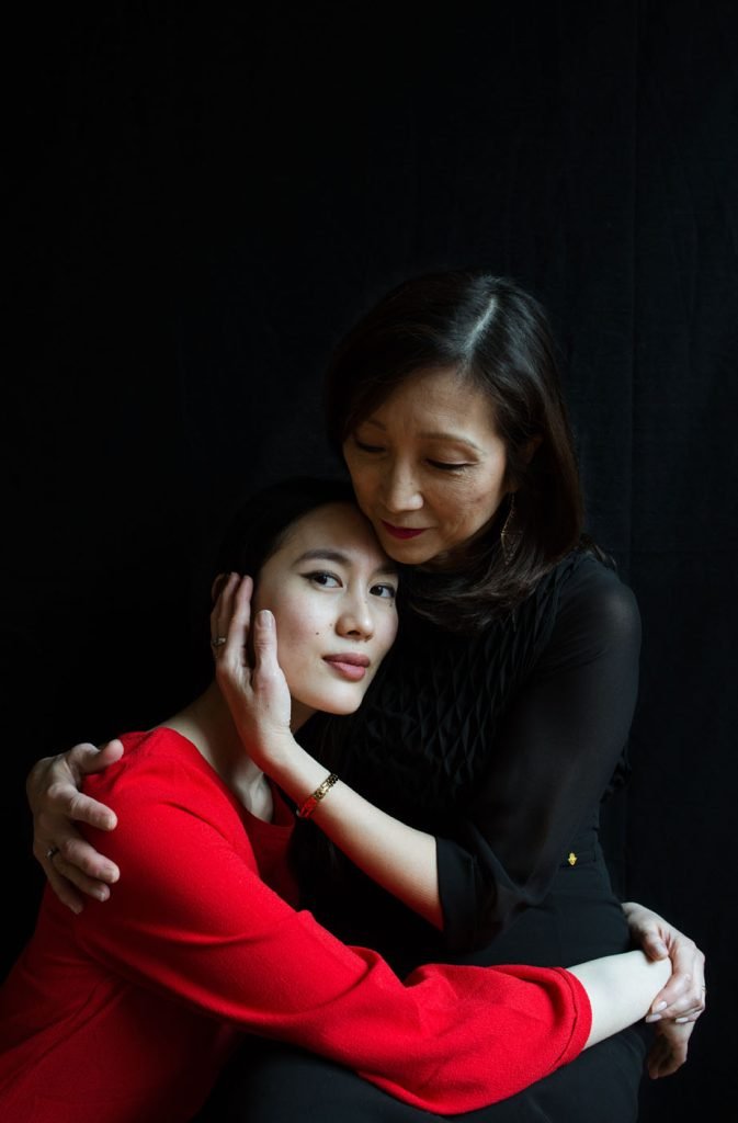 Mother holding her daughter against a dark background