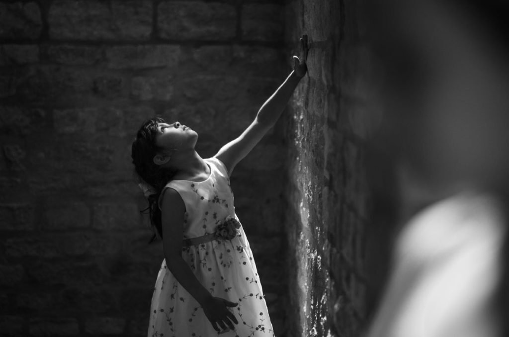 Girl reaching up to a wall fountain, black and white photograph