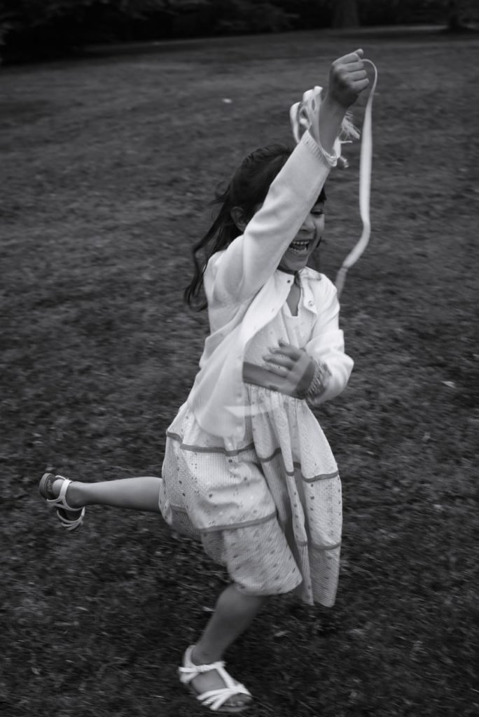 Girl running along a path with her arms in the air, black and white photograph