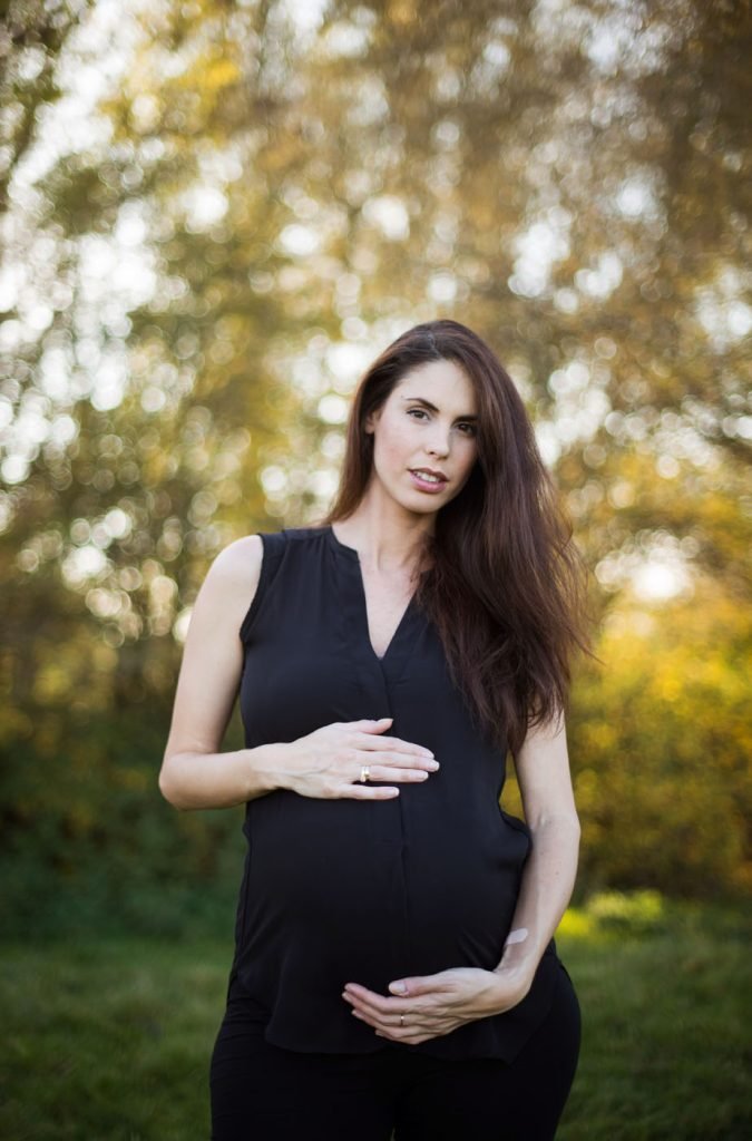 Expectant mother holding her bump in a park at golden hour