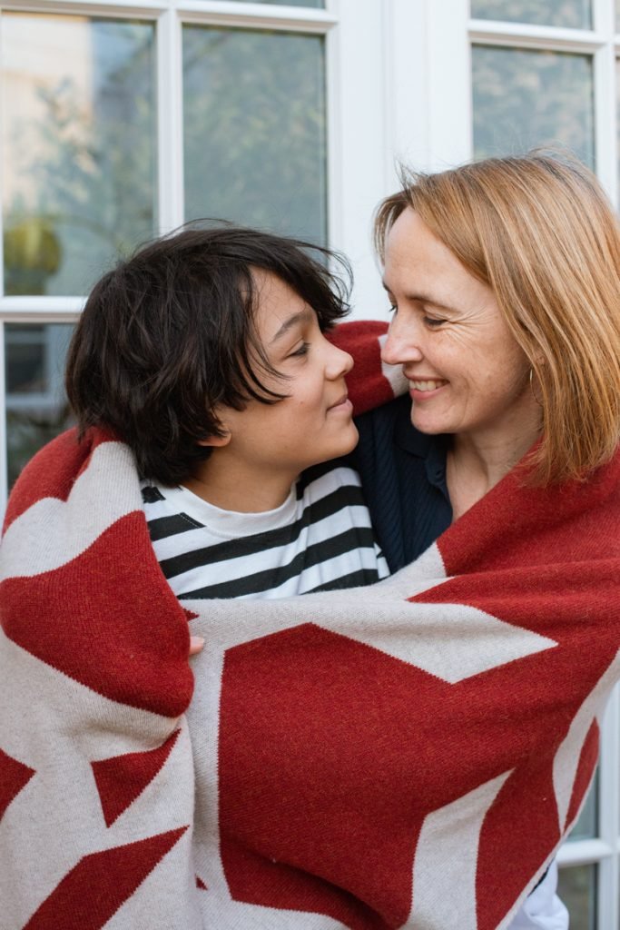 Mother and son wrapped together in a blanket, laughing