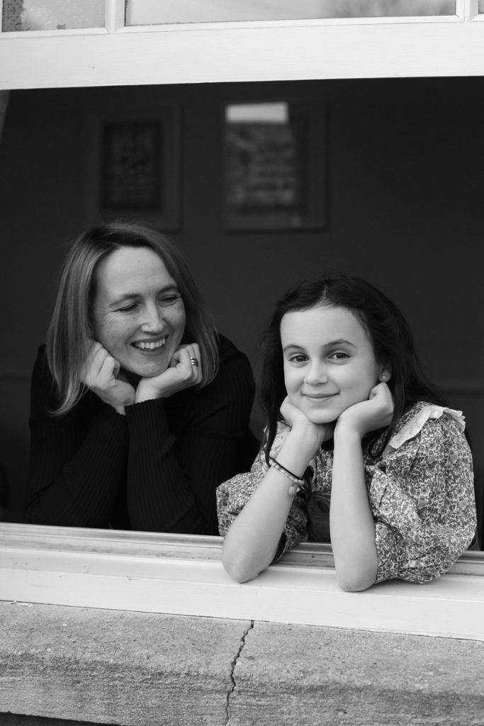 Mother and daughter leaning on a windowsill, chins in hands, black and white photograph