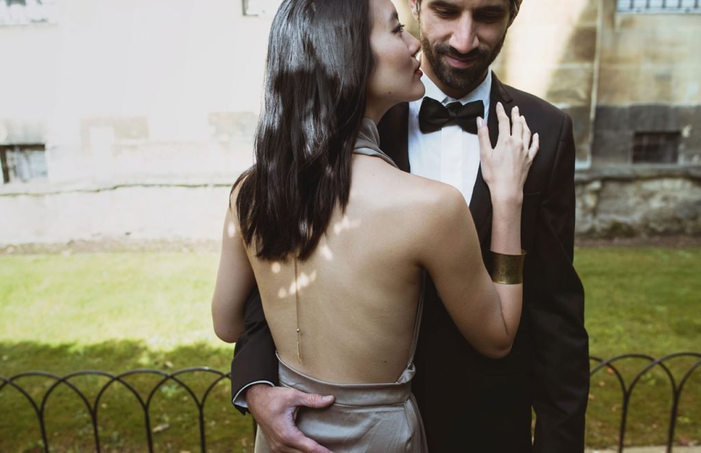 Couple in evening dress embracing on a college lawn