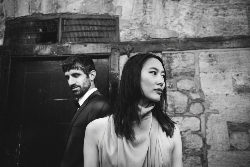 Couple standing against a stone wall, looking away from each other, black and white photograph