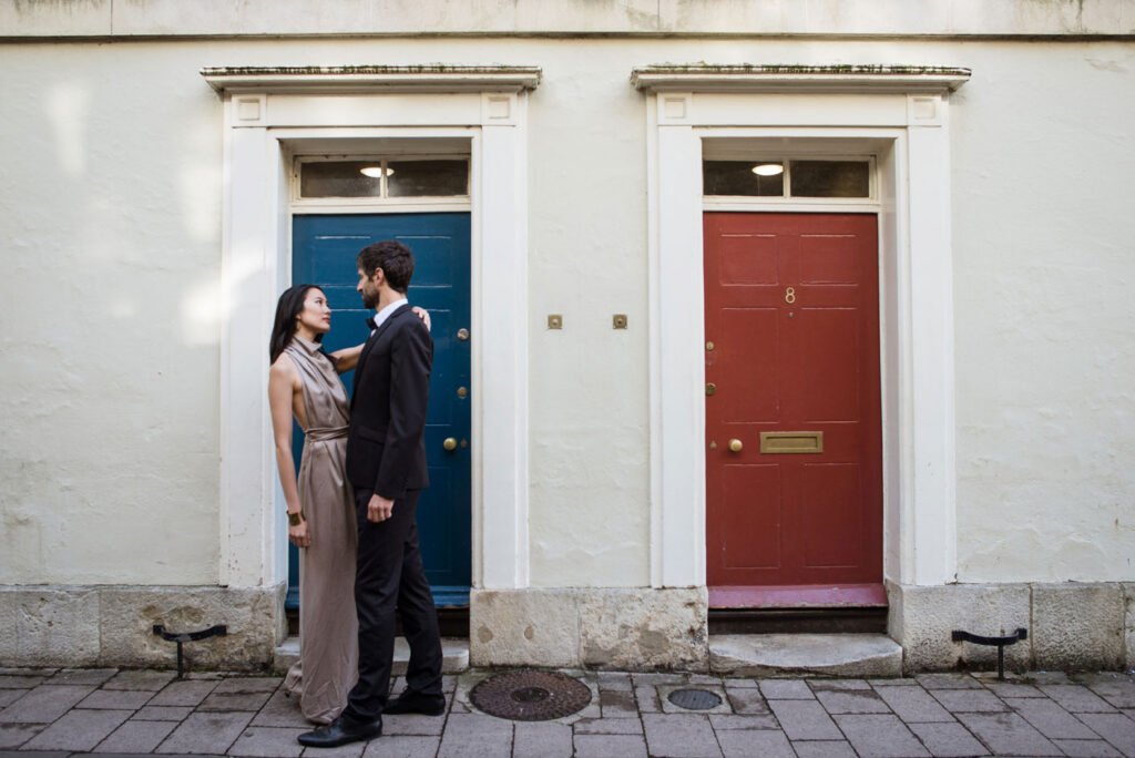 Couple facing each other between a blue and a red front door on a London terrace