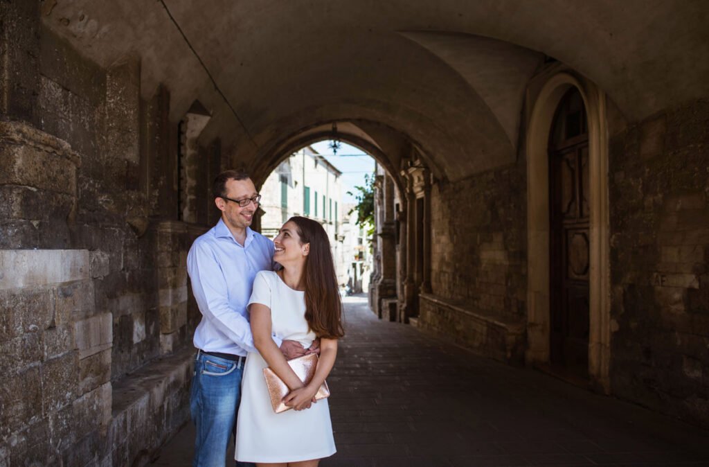 Couple embracing in a brick archway with the street beyond