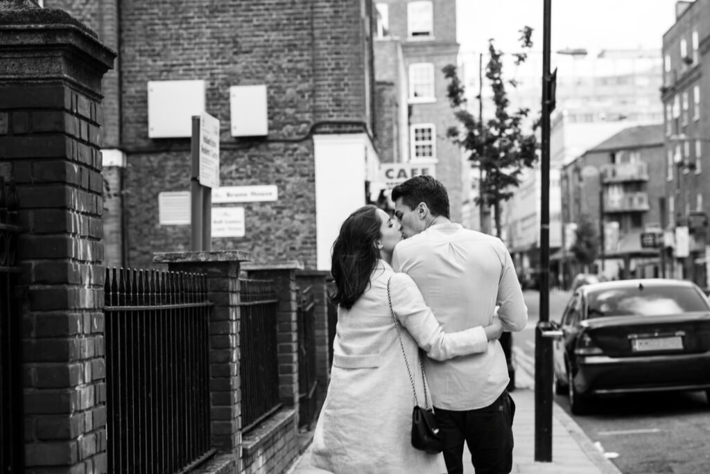 Couple walking away down a London street with their arms around each other, black and white photograph