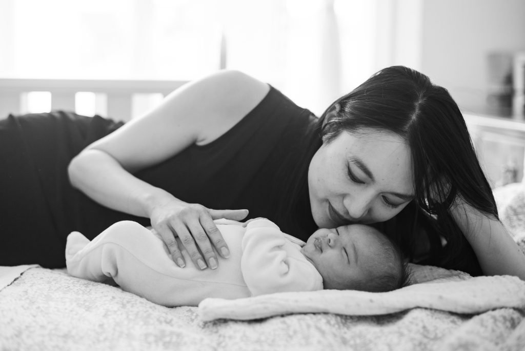 Mother lying beside her sleeping newborn, black and white photograph