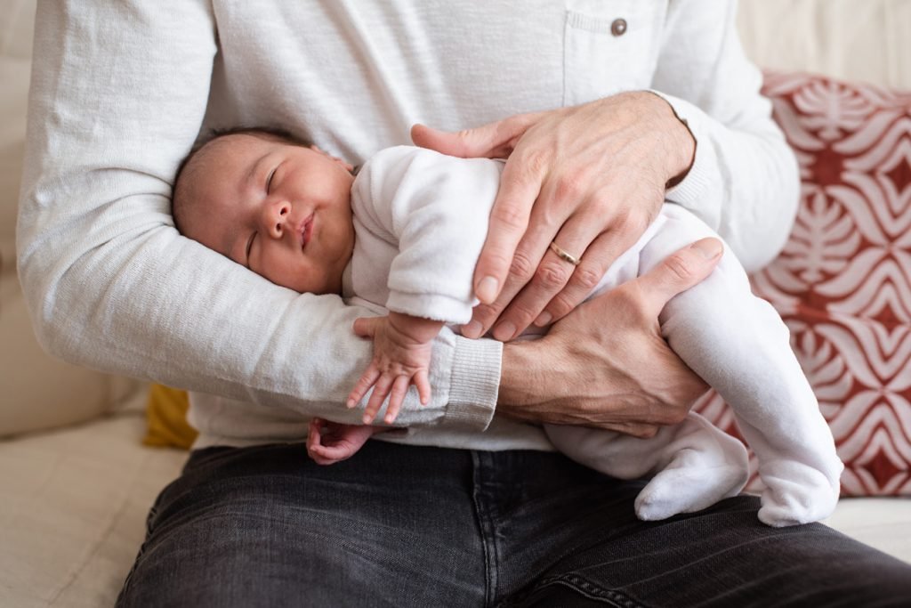 Father holding his sleeping newborn in the crook of his arm