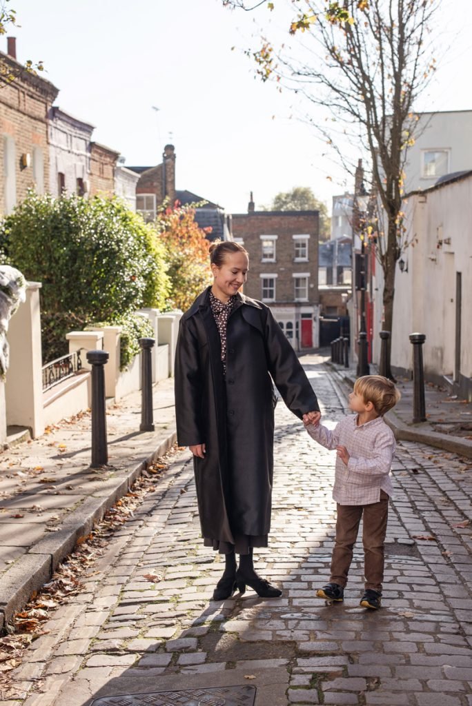 Mother and small child holding hands on a cobbled London street in autumn