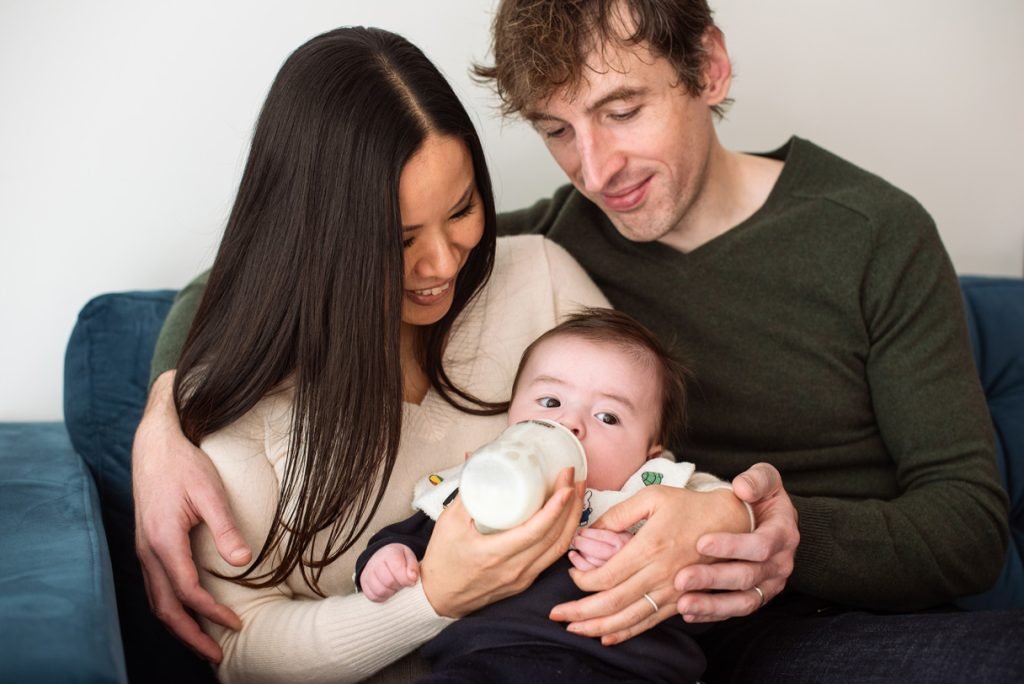 Parents on a sofa feeding their baby a bottle