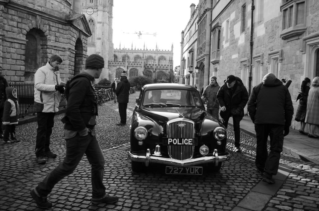 Vintage police car on a Cambridge street during a film shoot, black and white photograph