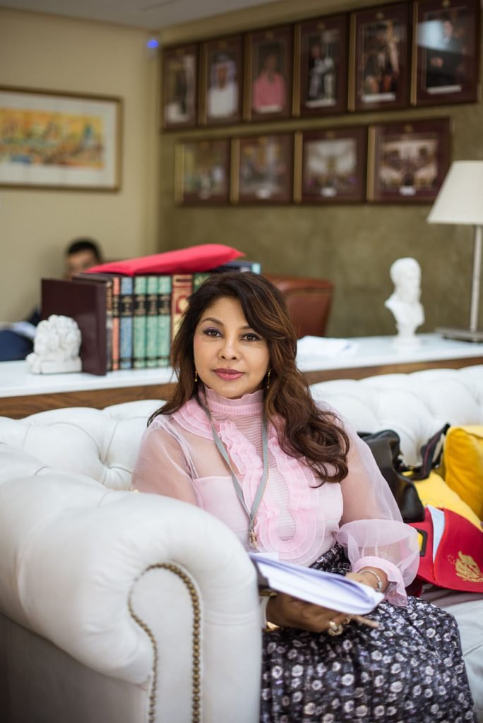 Guest sitting on a white sofa at an event, papers in her lap