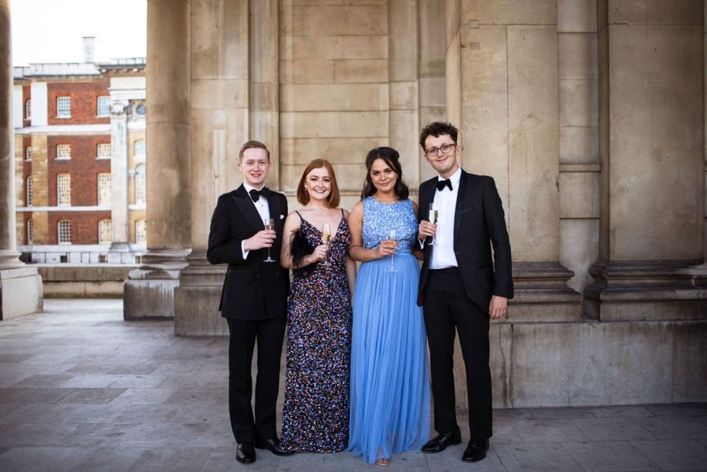 Four guests in evening dress with drinks in a colonnade