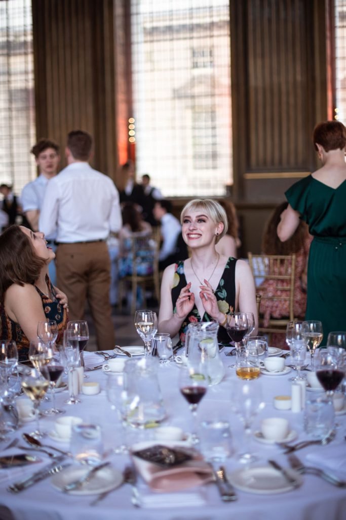 Guests standing and talking around a laid dinner table at a ball