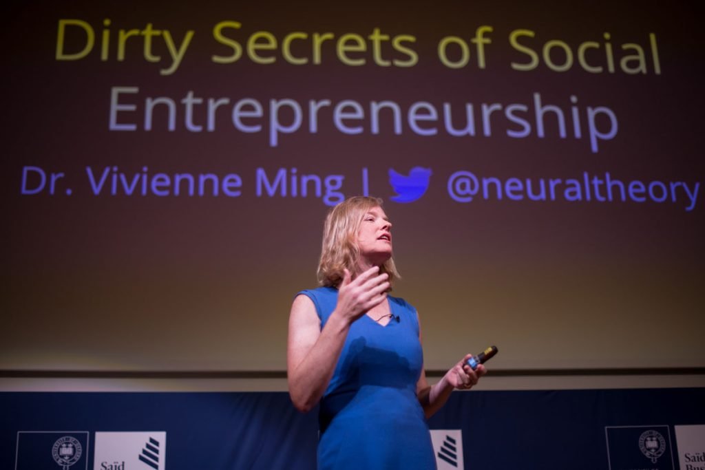 Speaker presenting a keynote in front of a projected title slide