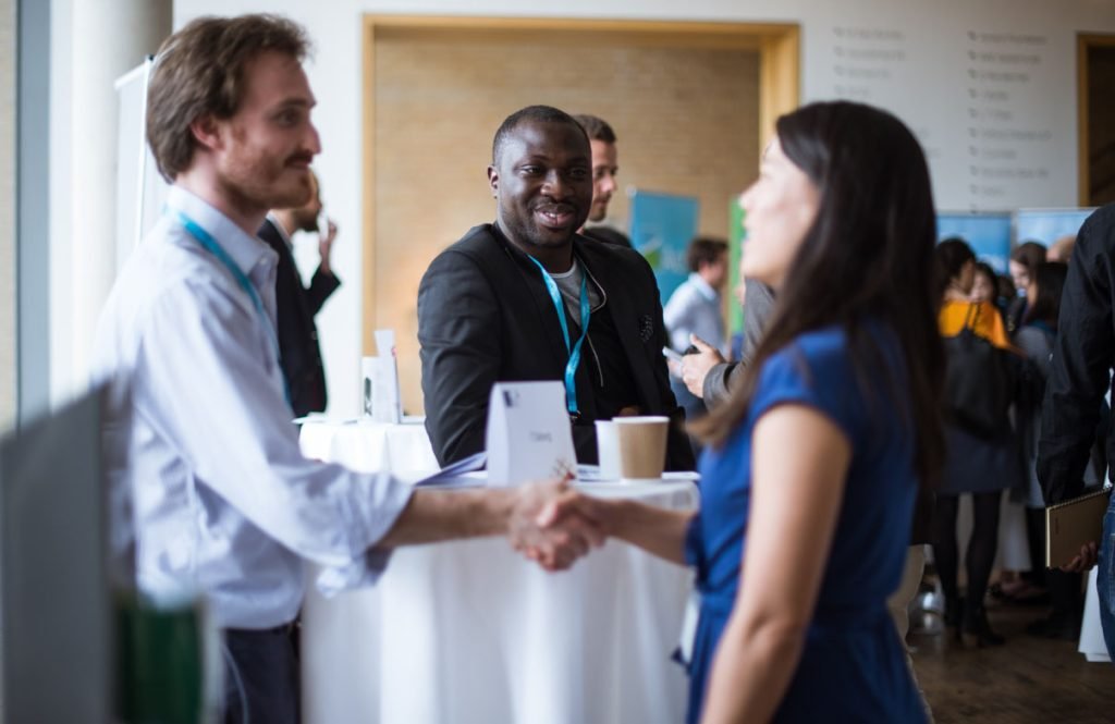 Delegates shaking hands over coffee at a conference