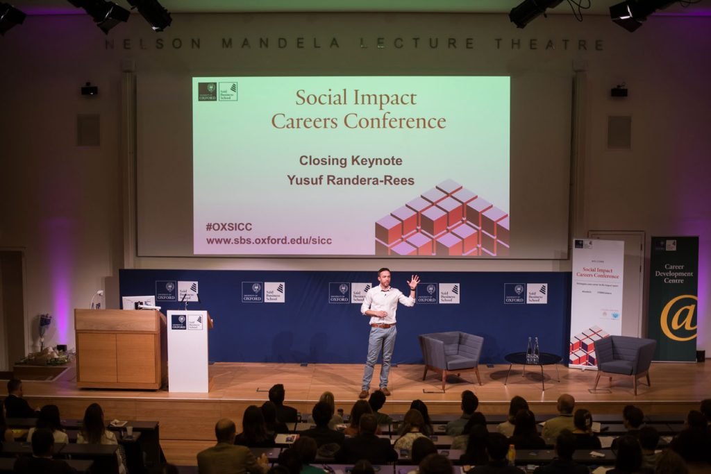 Speaker on stage at the Social Impact Careers Conference, audience seated in front