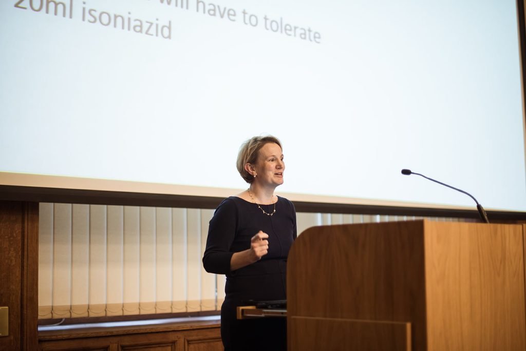 Speaker at a lectern beside a projected slide