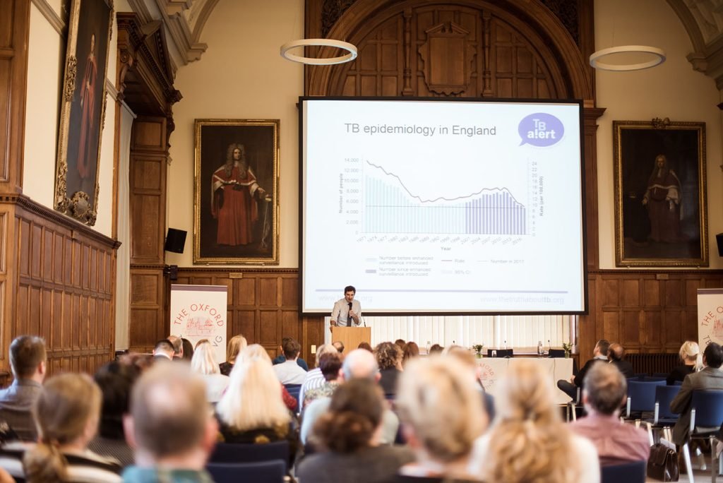Conference audience watching a presentation in a panelled hall