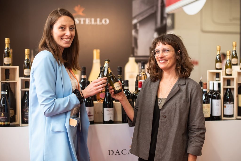 Two people talking over bottles at a wine tasting stand