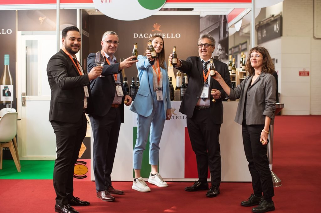 Exhibitors raising bottles for a photograph on a trade fair stand