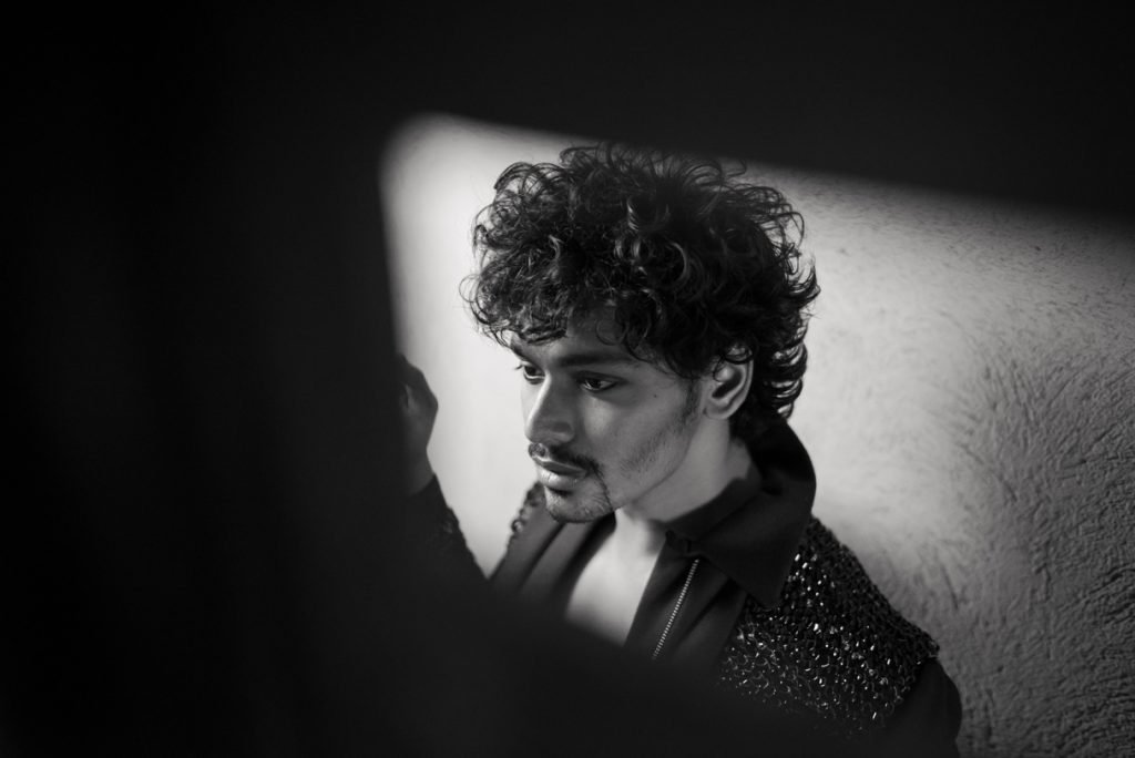Model in a sequinned jacket against a wall, black and white photograph