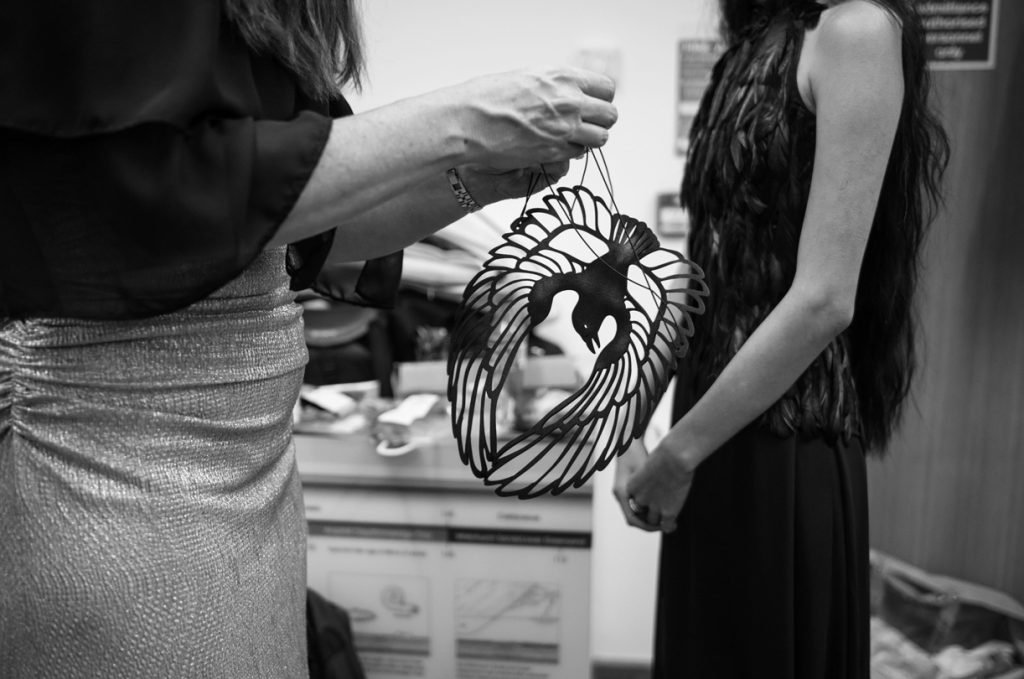 Dresser fitting a wire headpiece on a model backstage, black and white photograph