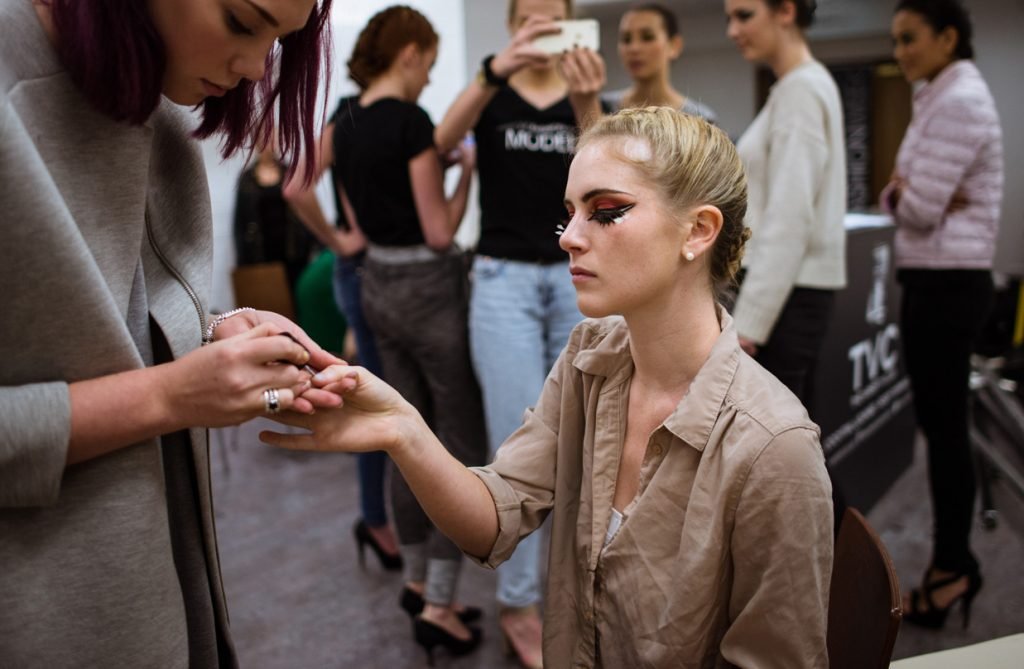 Model having her hand painted backstage before a show