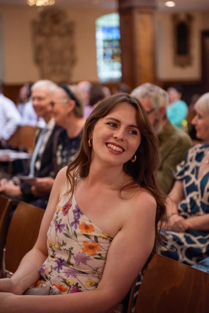 Wedding guest in a floral dress smiling in the congregation