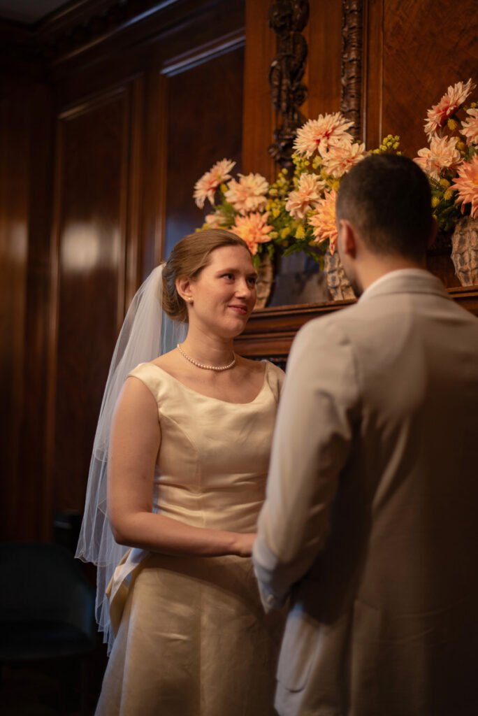 Bride and groom facing each other at the ceremony table, autumn dahlias behind them