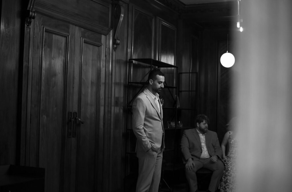 Groom waiting with his best man in a dark panelled room, black and white photograph