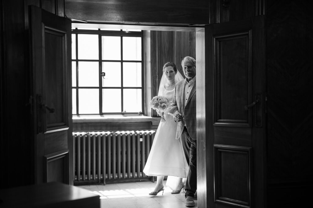 Bride waiting with her father in a doorway before the ceremony, black and white photograph