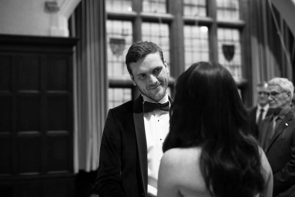 Groom in black tie talking with a guest, black and white photograph