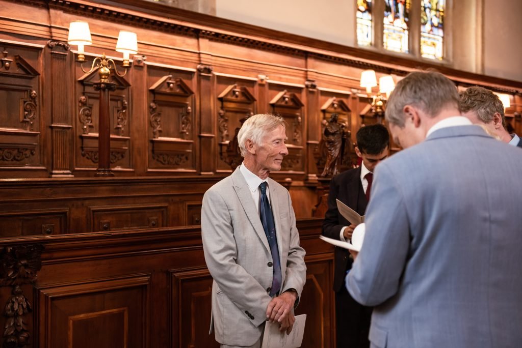 Guest waiting in a panelled college hall before the ceremony