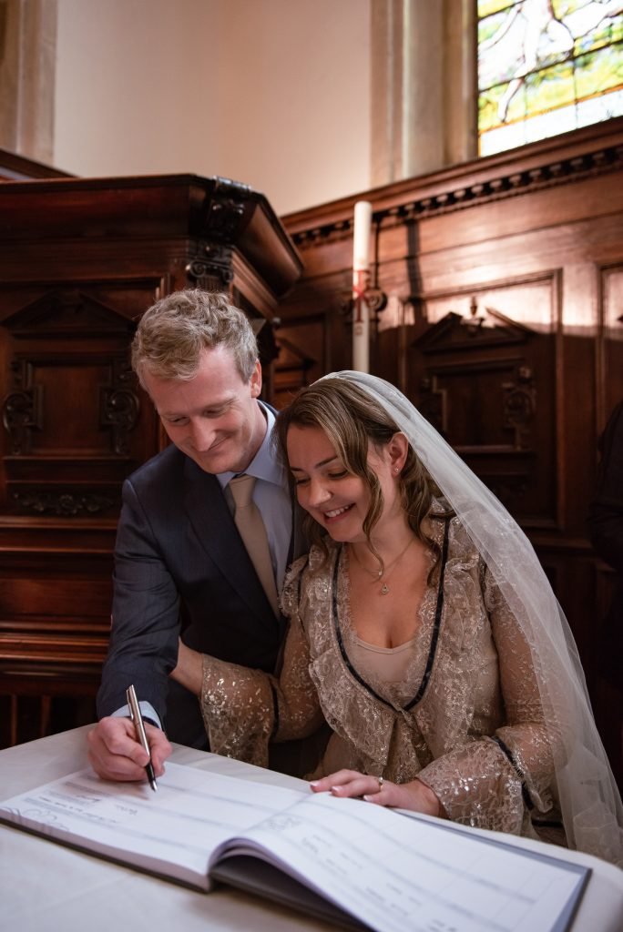 Groom and bride signing the register in a candlelit panelled room