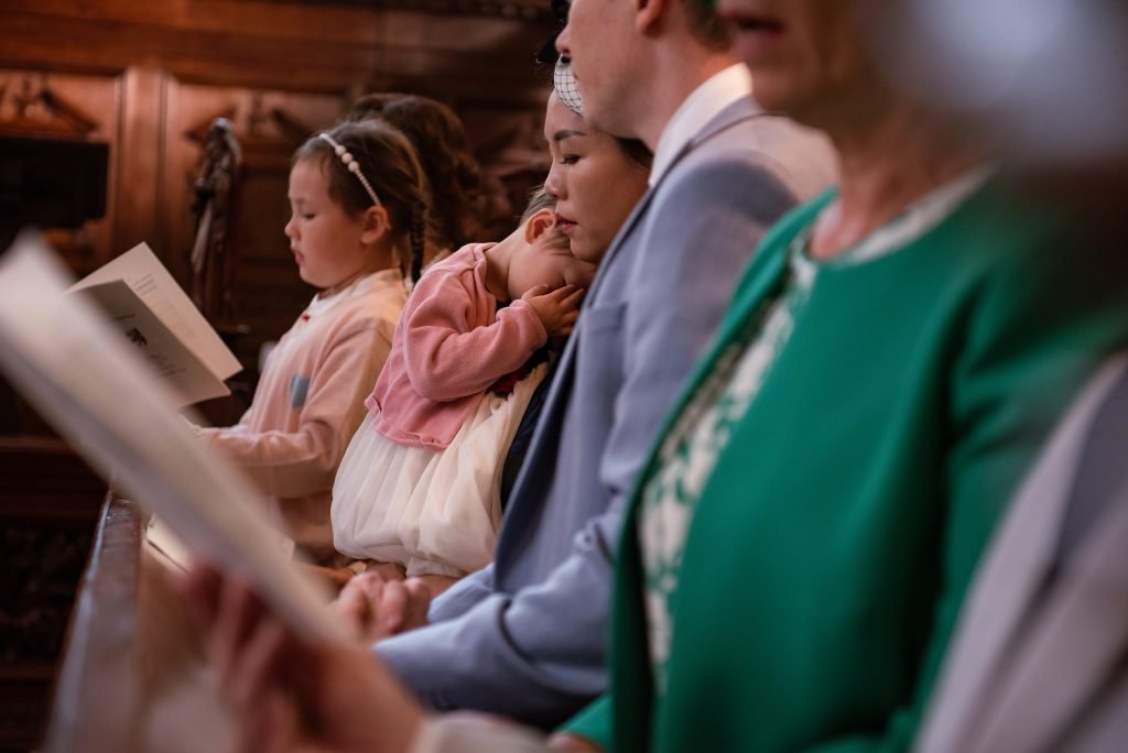Family seated in a row at the ceremony, a small girl among them