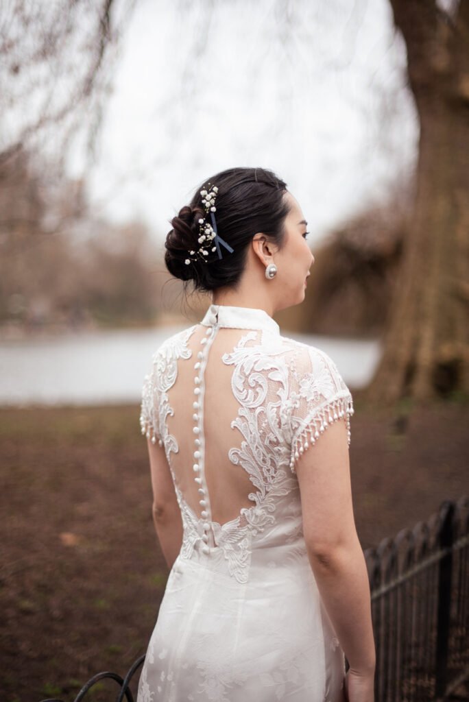 Back view of a bride's lace and button-fastened wedding dress beside a river