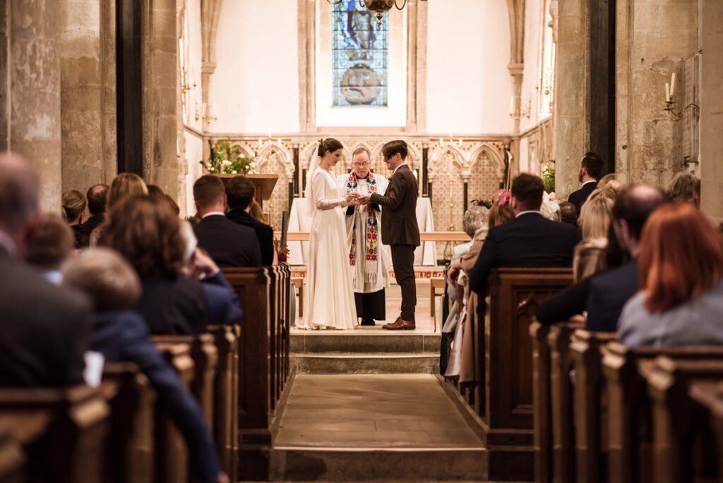 Wedding ceremony seen from the back of a village church, guests in the pews