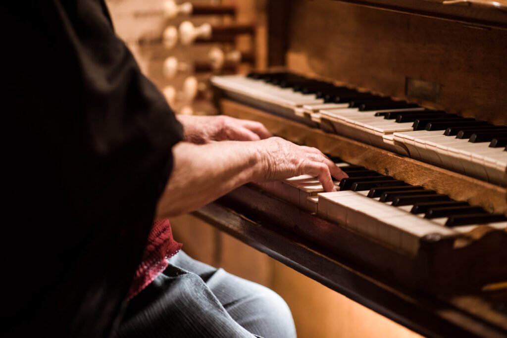 Older hands playing an upright piano at the reception