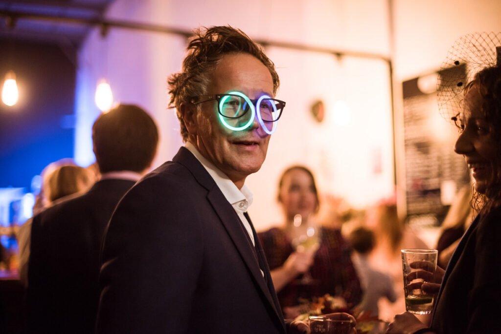 Wedding guest in novelty glasses laughing at the reception
